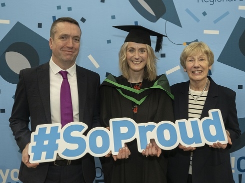 Group at graduation holding prop