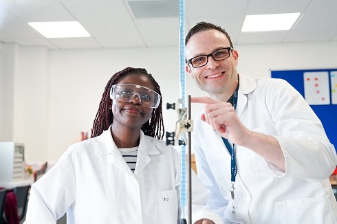Male and female wearing white coats in science lab