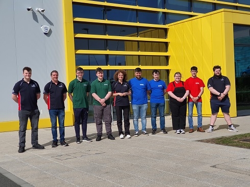 Group of apprentices and staff standing outside FANUC building